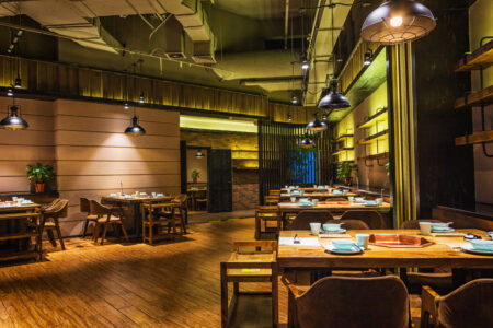 Salle de restaurant, on voit les couverts sur les tables. La salle est vide