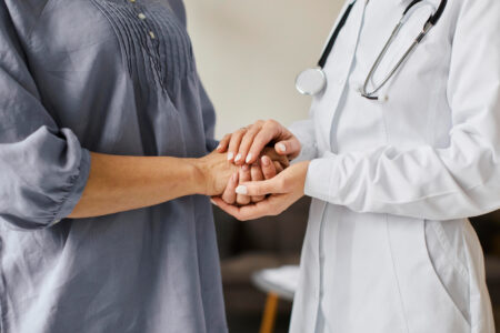 deux personnes dont une personne soignante qui tient les mains de la patiente